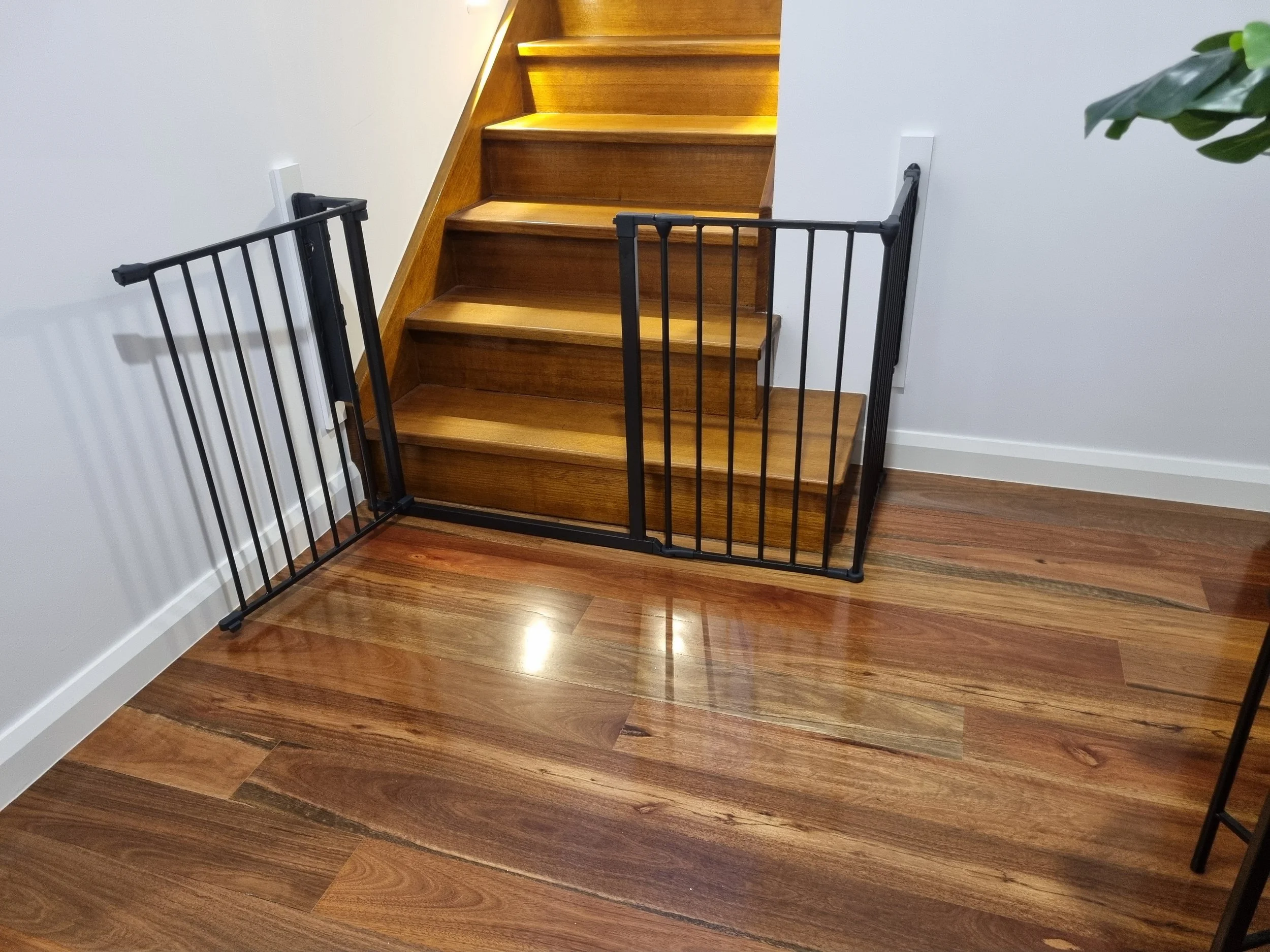 Black baby gate across the bottom of timber stairs