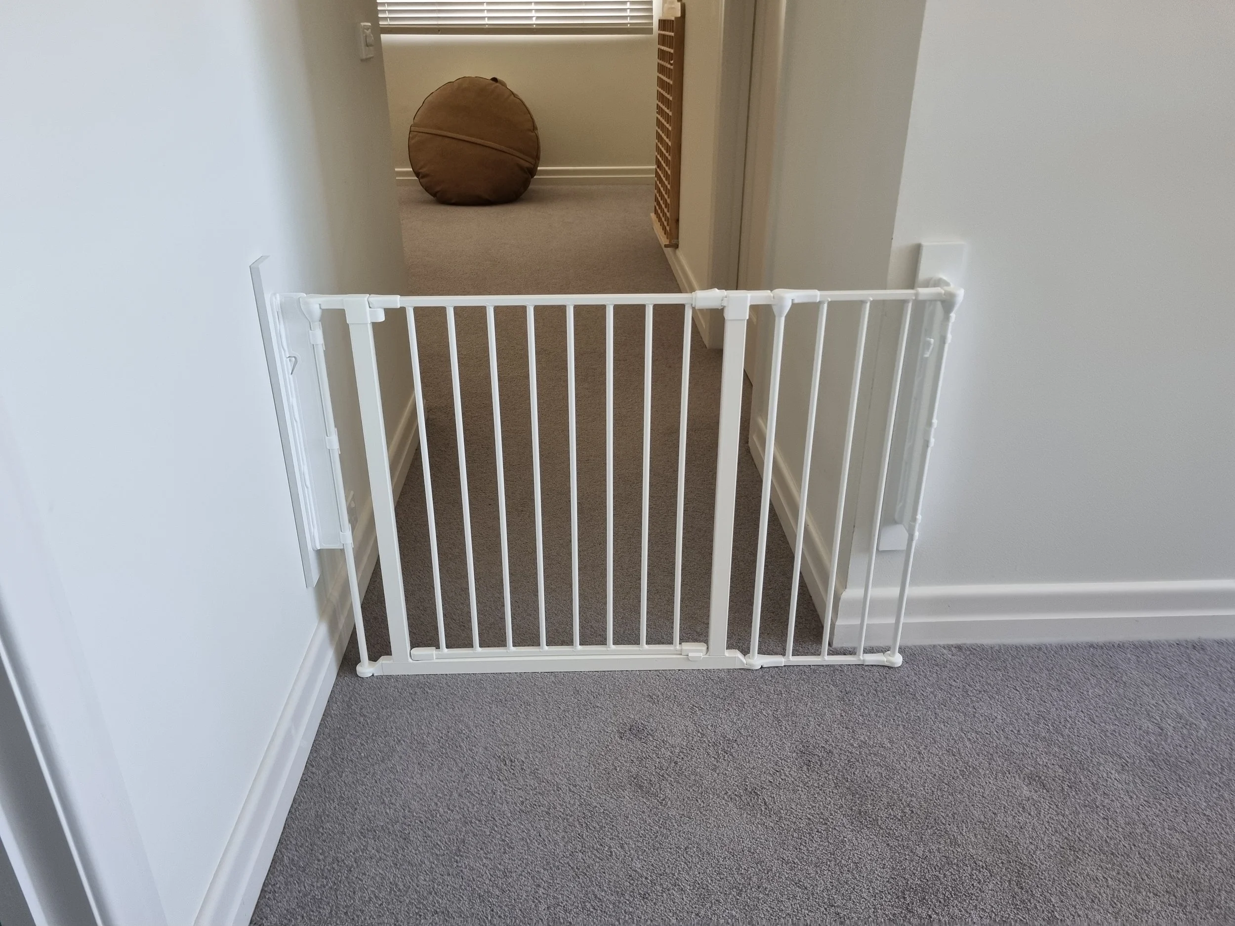 White baby gate across a carpeted hallway