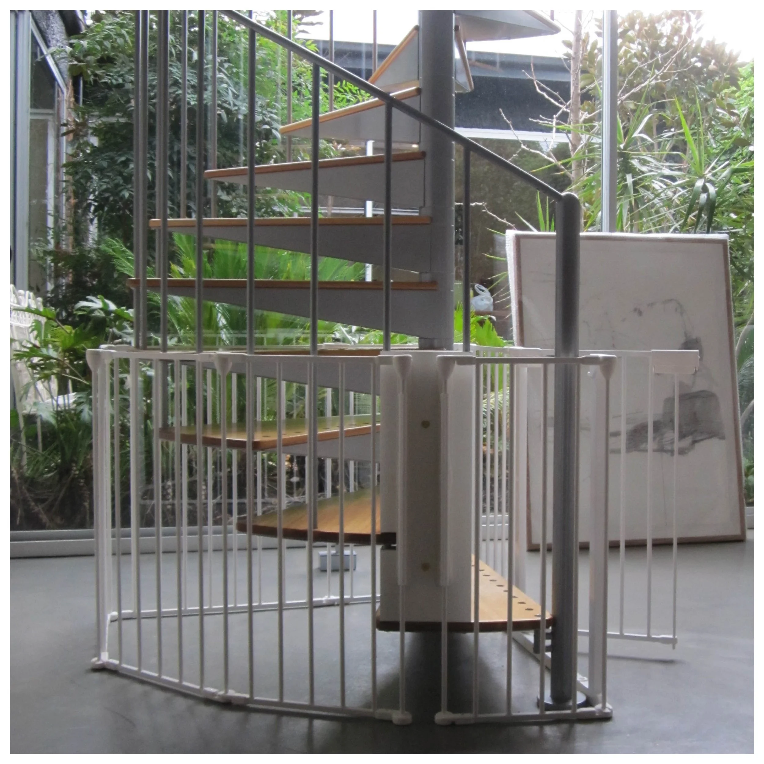 White baby gate surrounding the base of a spiral staircase with timber treads