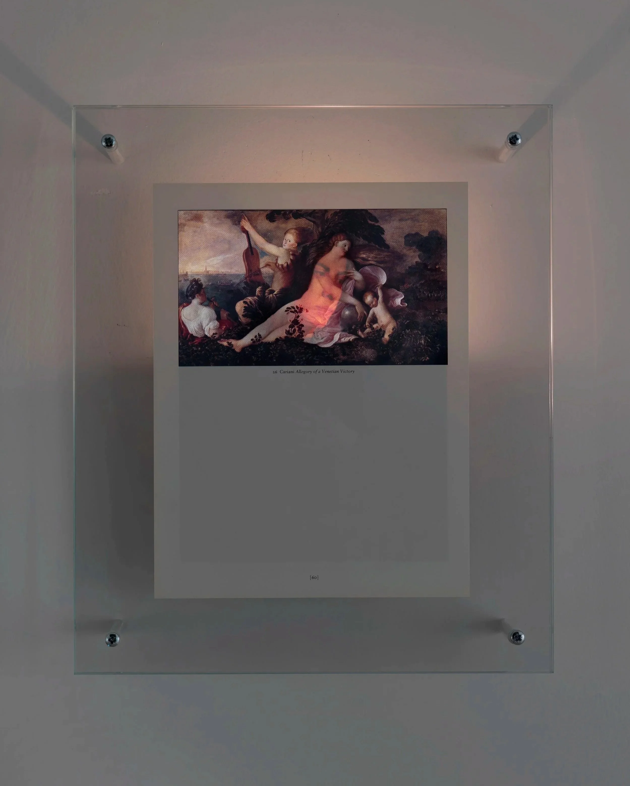 Detail of Mark Wallinger’s Genius of Venice (1991) framed art piece displayed on a gallery wall, sandwiched between glass and illuminated from behind by a flickering nightlight to reveal the presence of an image overleaf. 