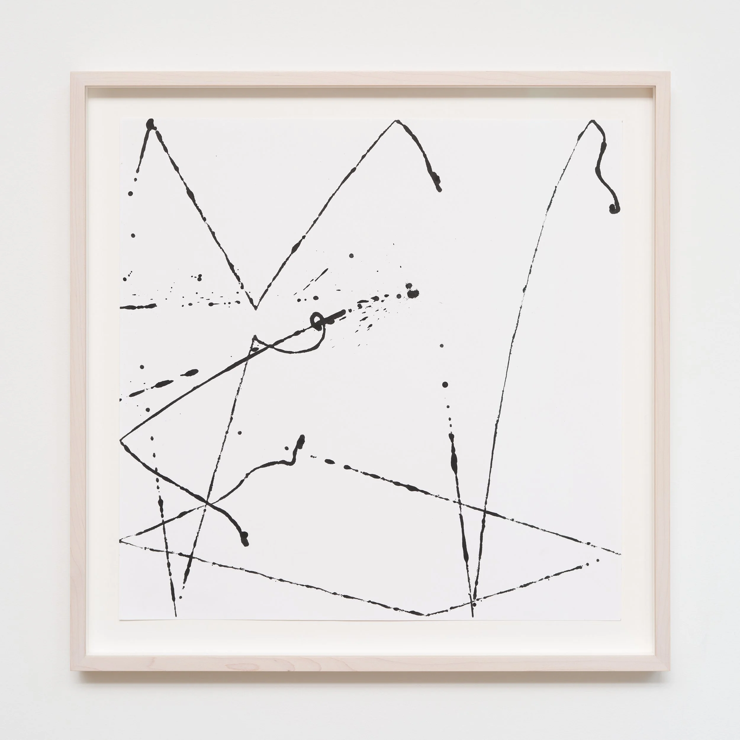 Abstract black ink splatter and line drawing on white canvas framed in light wood, resembling a modern art piece.