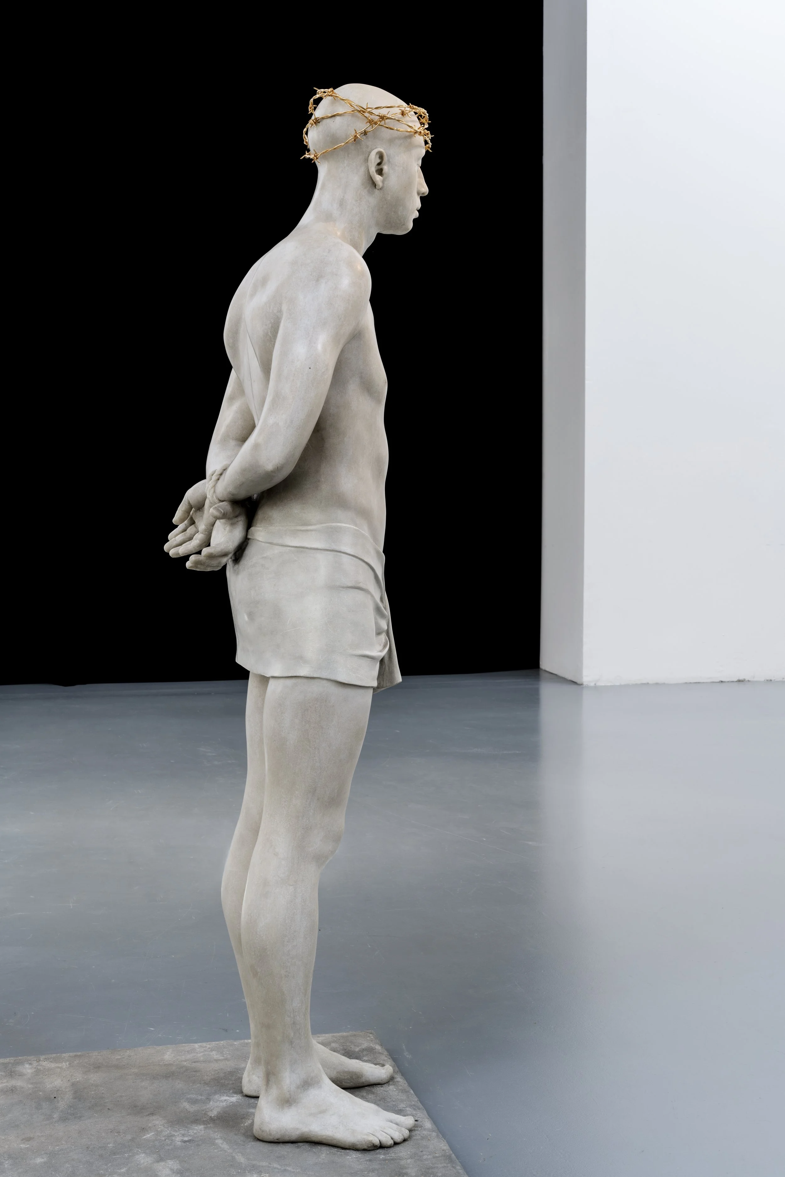 A museum gallery presenting Mark Wallinger’s Ecce Homo (1999-2000) , a life-sized, white marble resin sculpture of a vulnerable, solitary Christ figure.