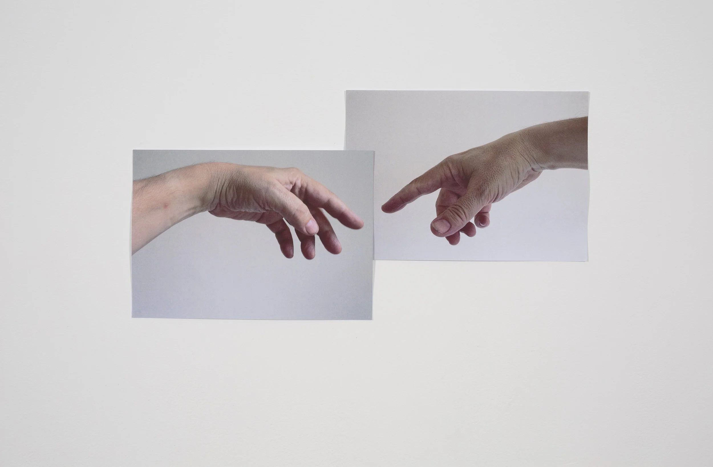 Gallery wall featuring Mark Wallinger’s Ego: two photographs of the artist’s hands reaching toward each other, evoking the iconic Creation of Adam scene.