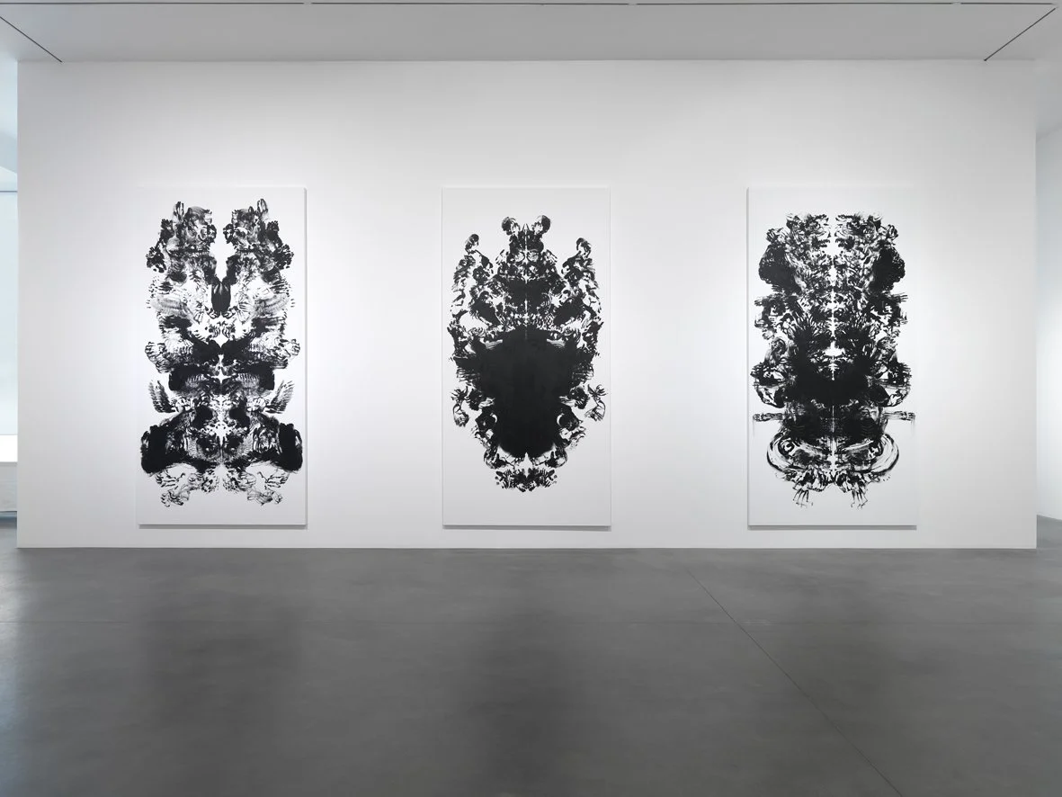 Three large In a bright gallery, Mark Wallinger’s id paintings (2015), scaled to his body, line the walls. The mirrored halves evoke the Vitruvian Man and Rorschach inkblots, created by sweeping paint-covered hands across the canvas.