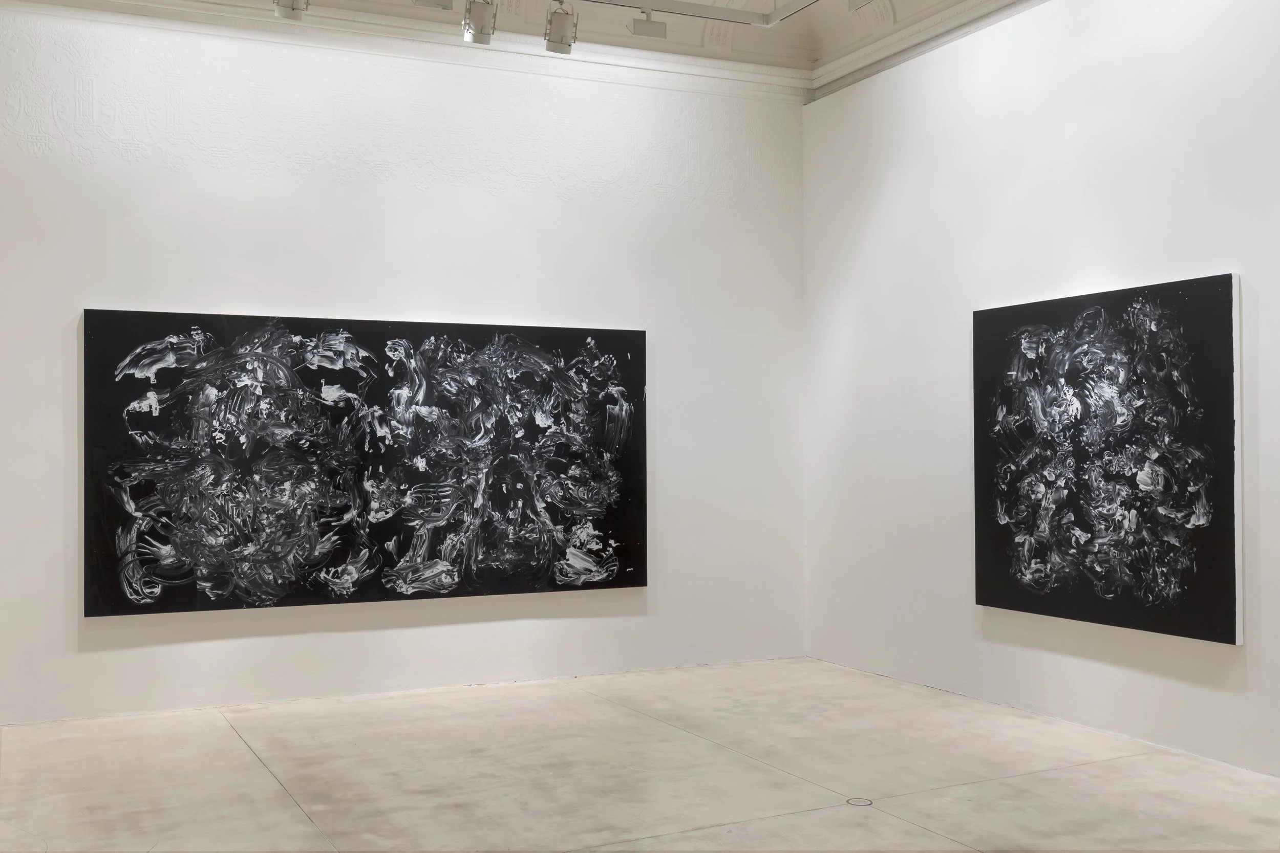 Two large abstract black and white paintings displayed on white gallery walls.