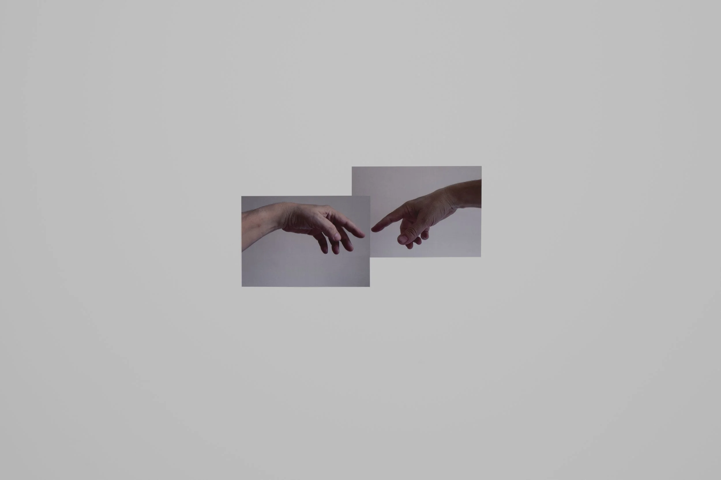 Two hands reaching towards each other, with one on the left and the other on the right against a plain background.