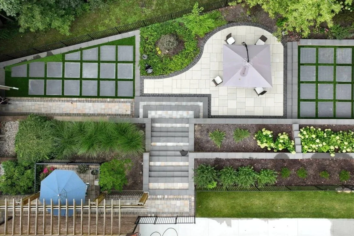 Overhead view of a terraced backyard with a curved patio, steps and planting beds — Premier Landscaping