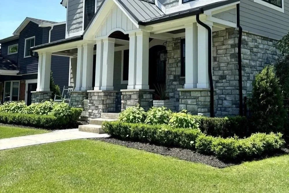 Craftsman home framed by boxwood hedges, hydrangeas and arborvitae above a lush front lawn — Premier Landscaping