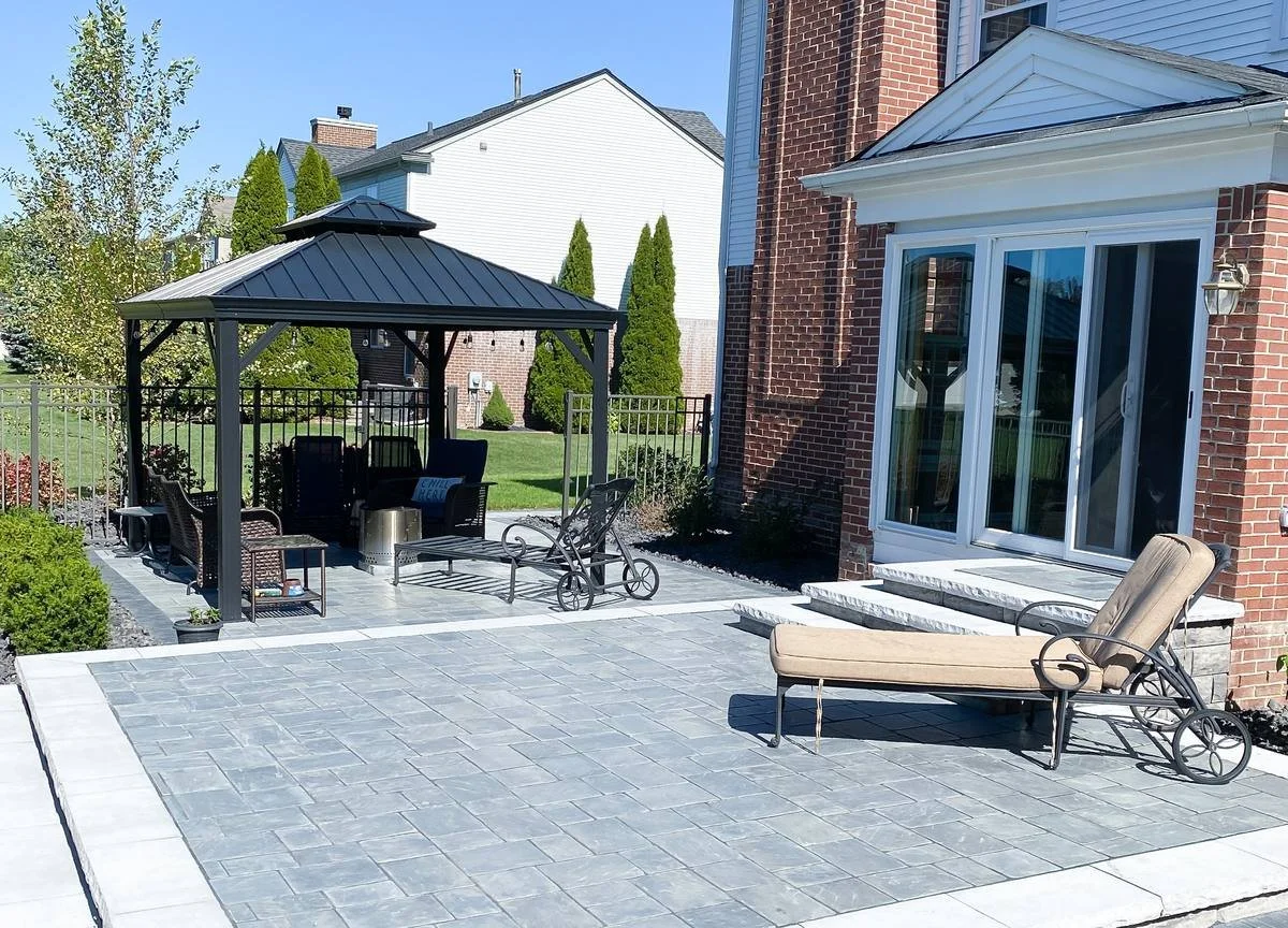 Gray paver patio with a light stone border leading to a gazebo seating area — Premier Landscaping