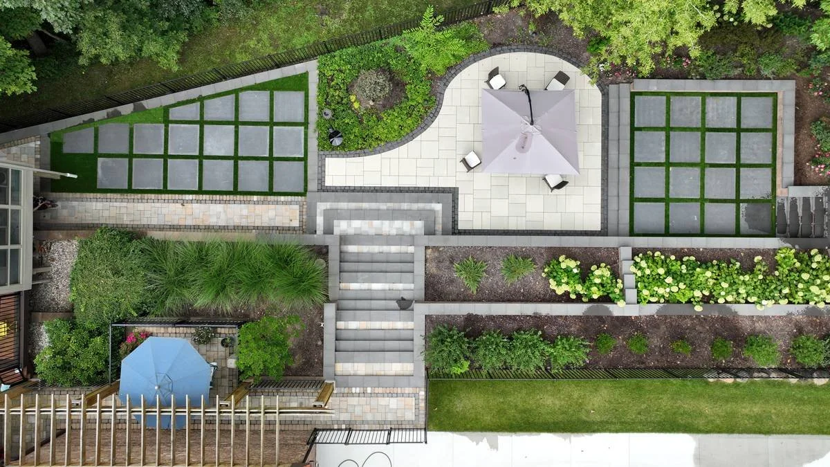 Curved patio with umbrella seating, turf grid pavers and hydrangea beds from above — Premier Landscaping