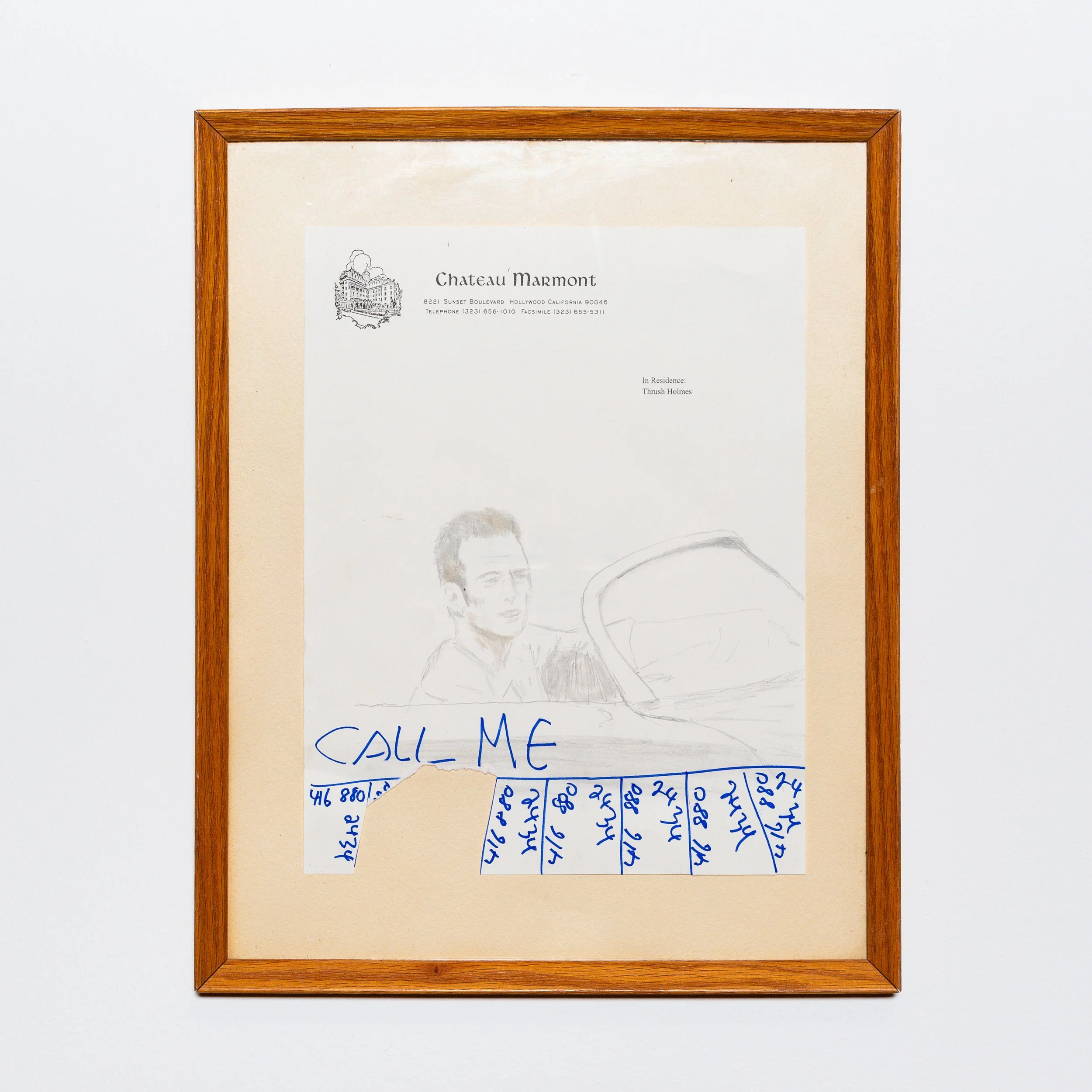 A framed piece of paper with a hand-drawn sketch of a person and the words 'Call Me' written in blue ink, with handwritten notes or numbers at the bottom.