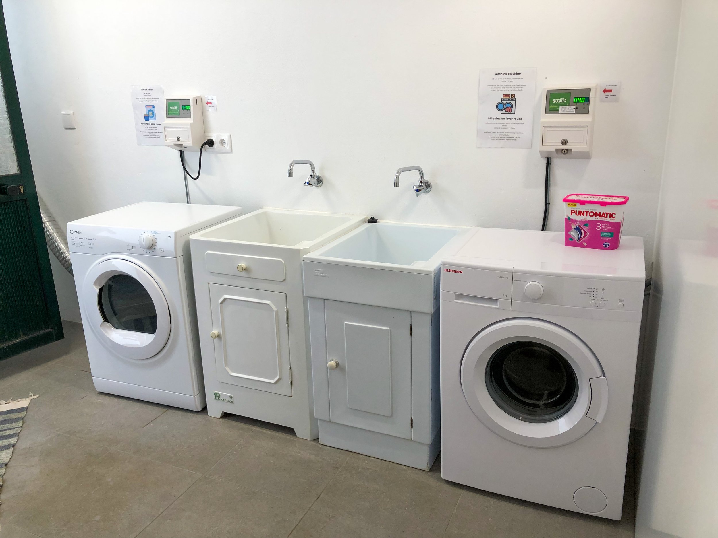 Self-service laundry with washing machine, dryer and hand washing basins.