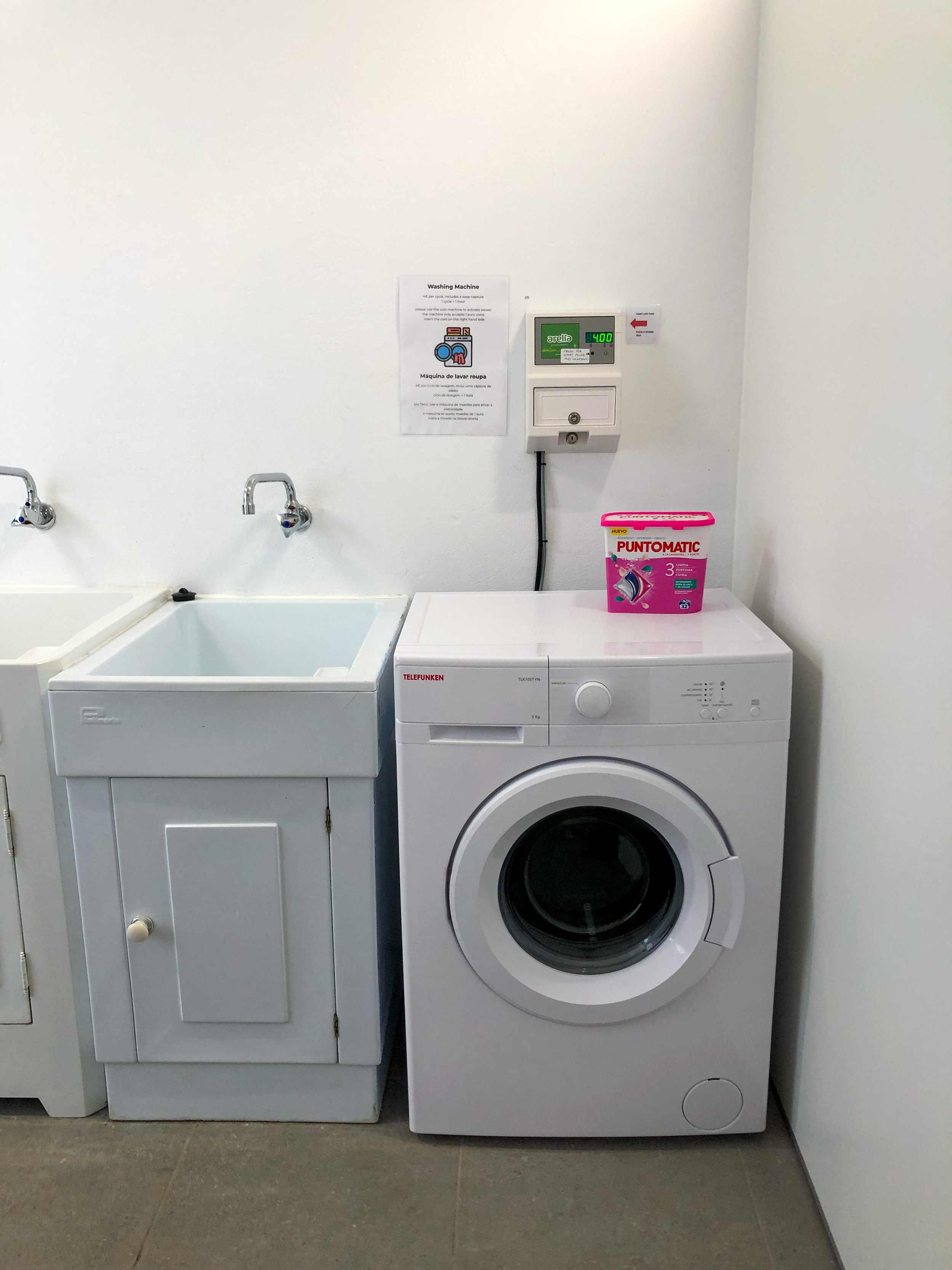 Self-service laundry with washing machine, dryer and hand washing basins.