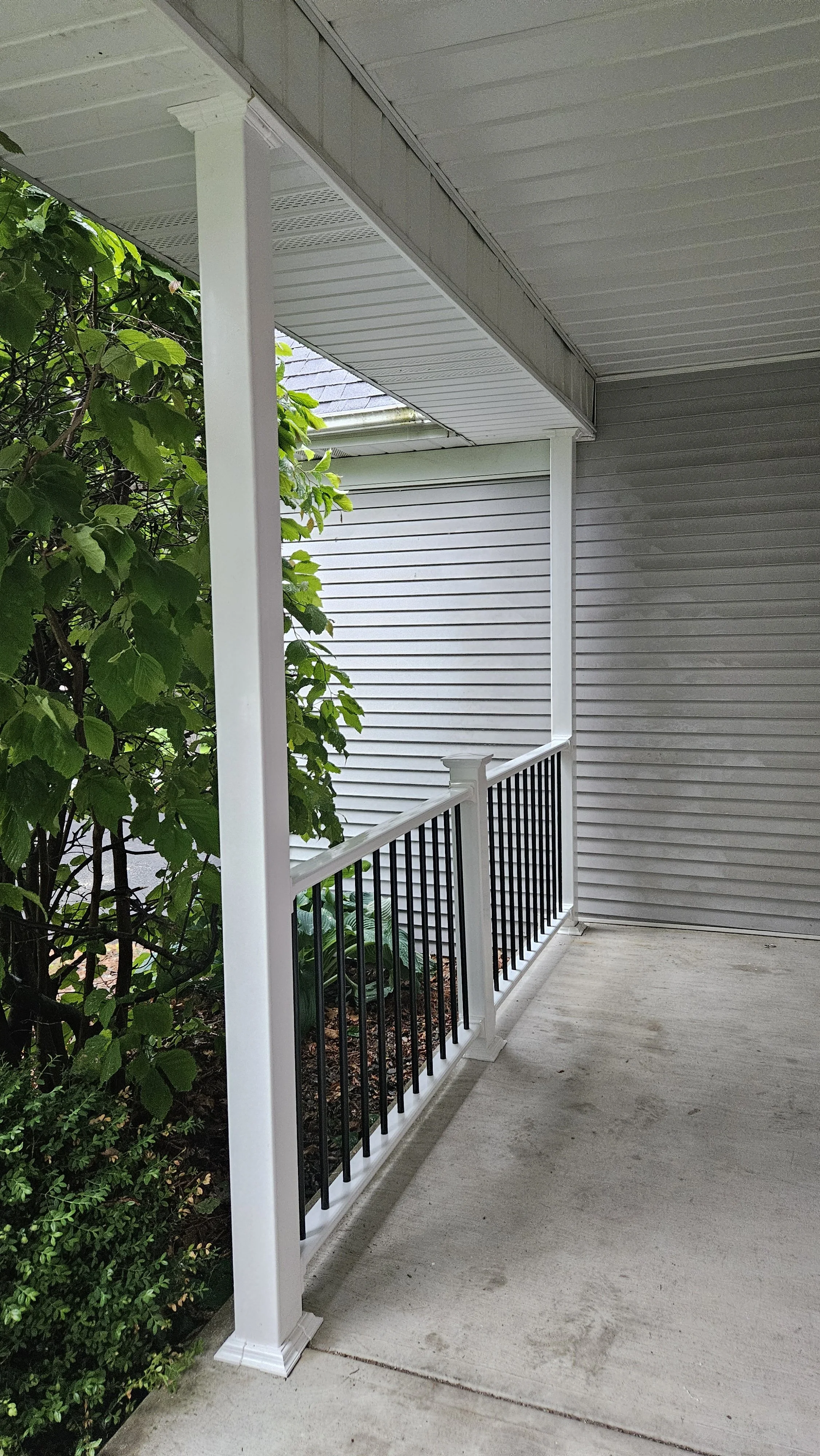 After: new white posts, fresh railings, black metal spindles, and clean post base trim for a brighter, more modern railing rebuild. 