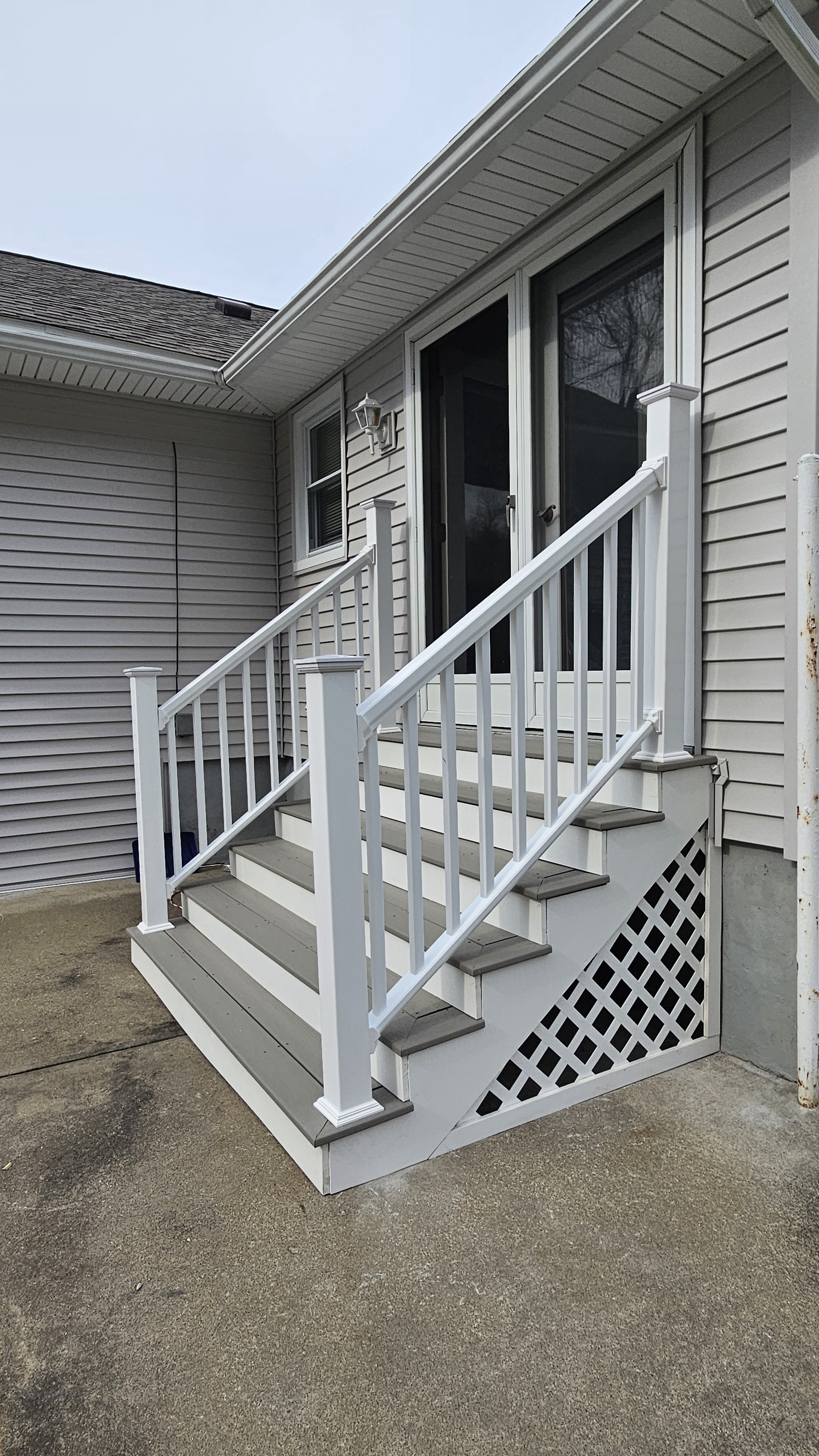 AFTER: complete back entrance stair rebuild with Trex decking and vinyl railings for a cleaner, safer, and more updated entrance. 