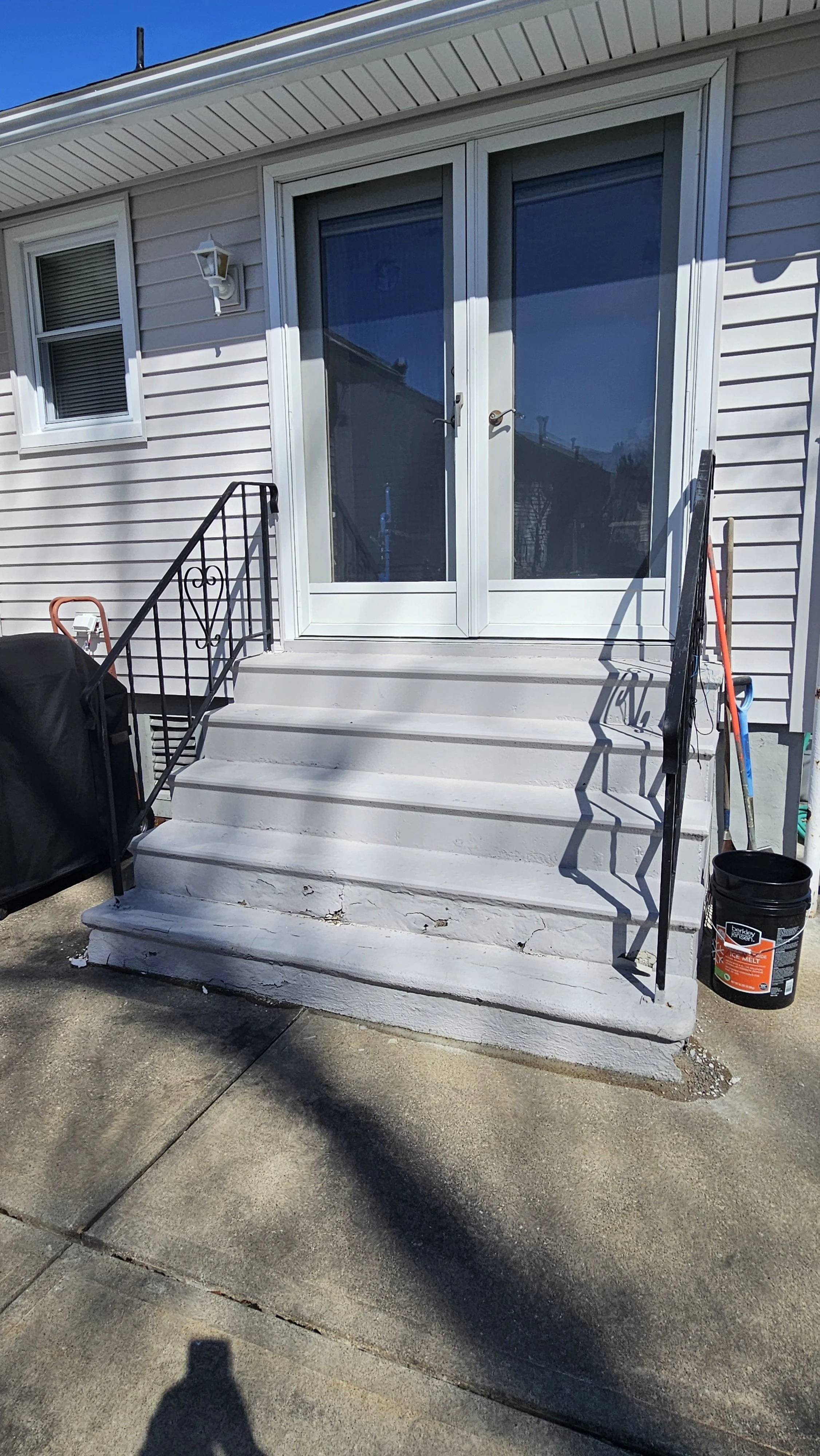 BEFORE: old concrete back entrance steps with metal railings before the stair rebuild and railing upgrade. 