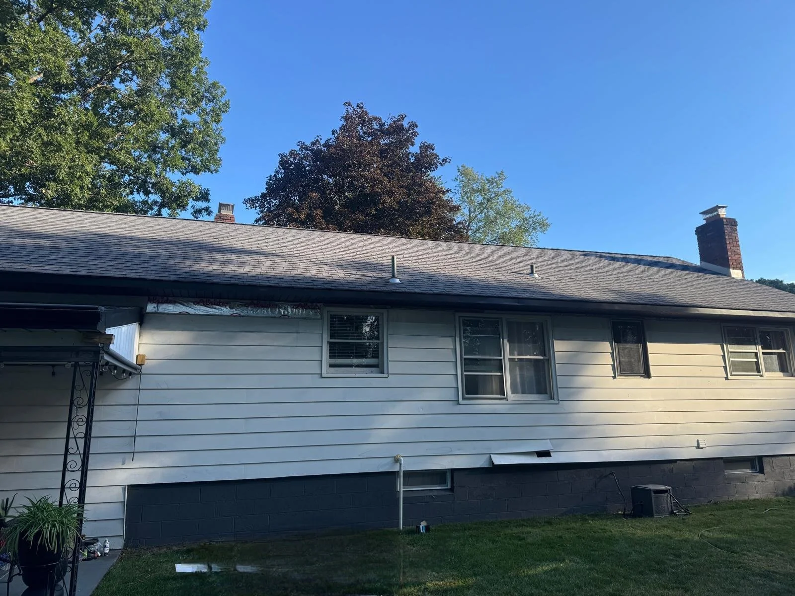 Before: This Schenectady, NY backyard had no deck or outdoor living space-just the original siding and windows. Regional Remodeling transformed the exterior with new siding, modern black new-construction windows, and a  custom composite deck and comp