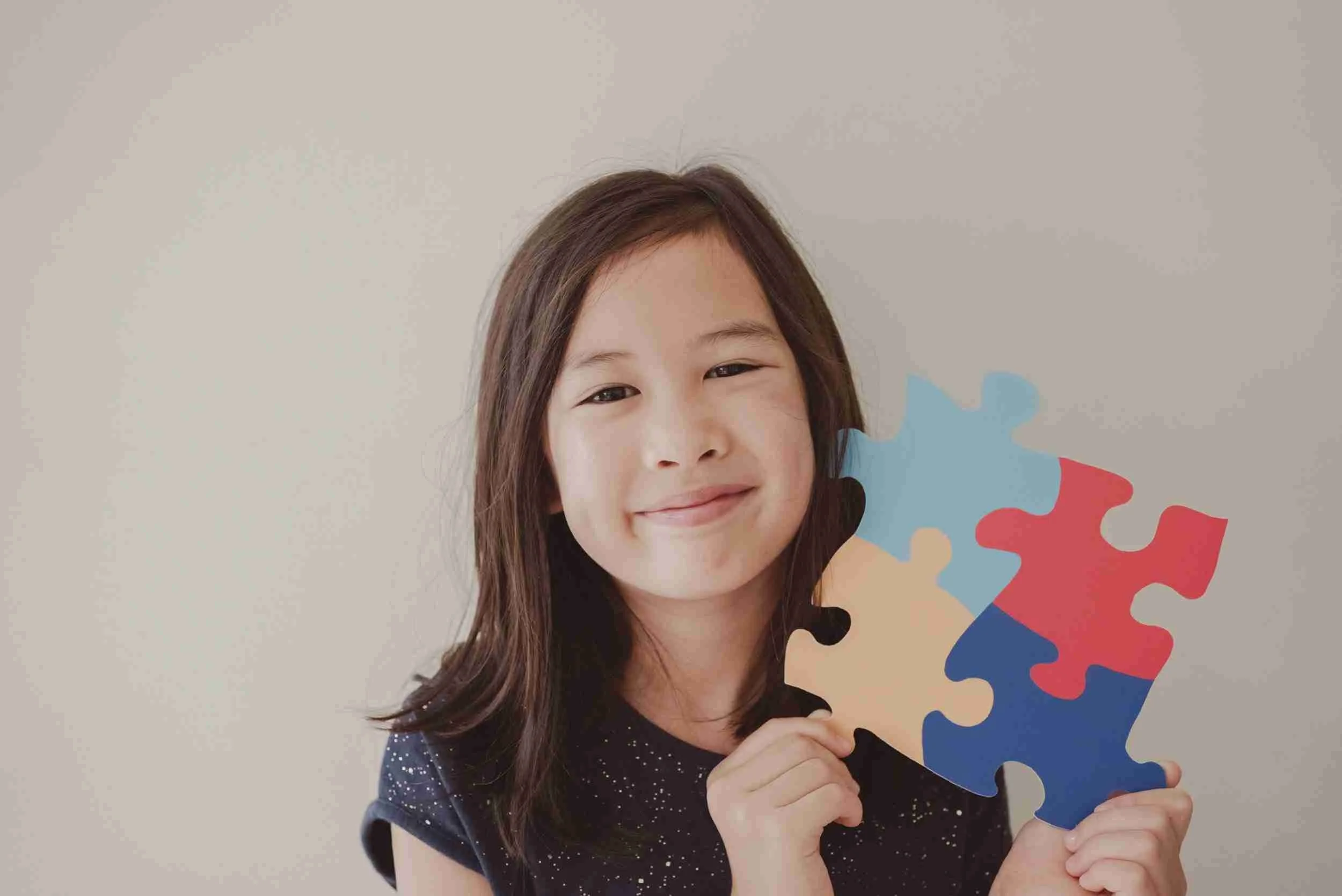 Smiling child holding colorful puzzle pieces.