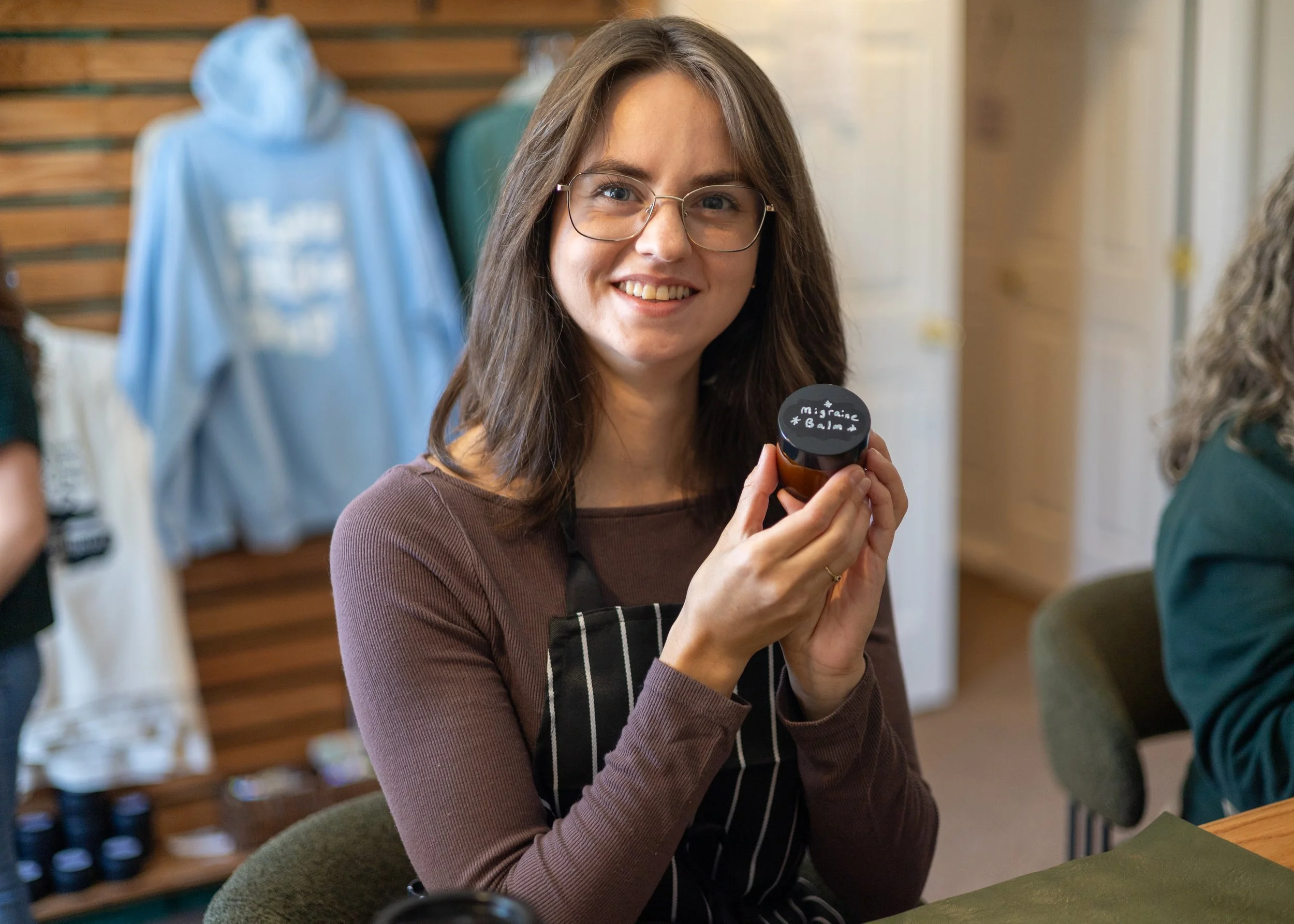 A soft opening customer poses with her handmade migrane balm.