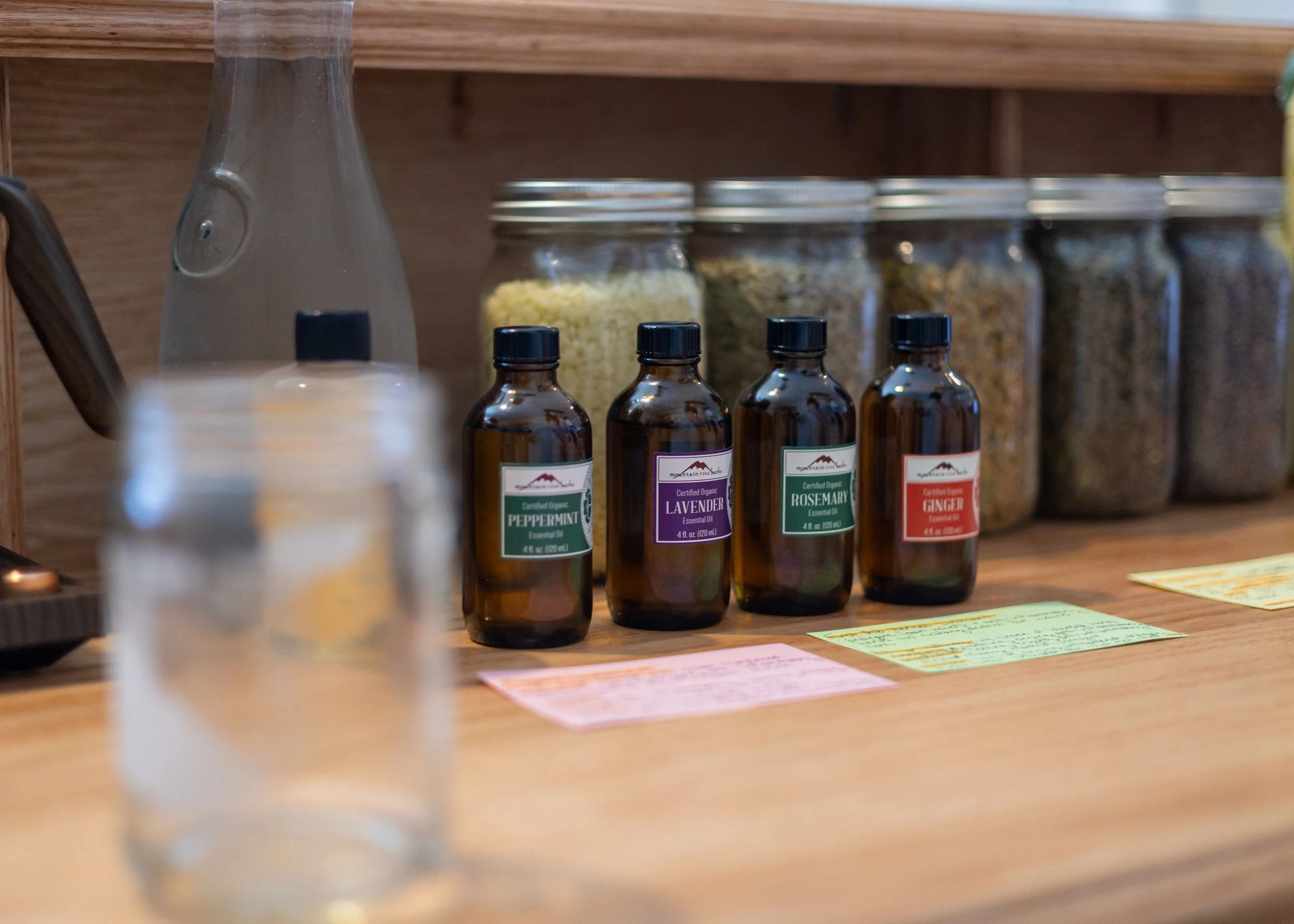 A collection of essential oils and herbs behind the Herbal Bar.