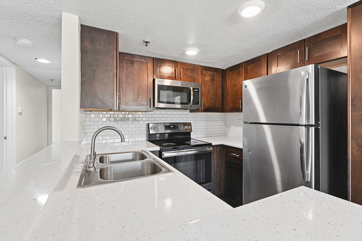 Gorgeous Kitchen in Citrus Heights Apartment Homes with plank flooring, quartz countertops, stainless appliances and dark wood cabinetry. 