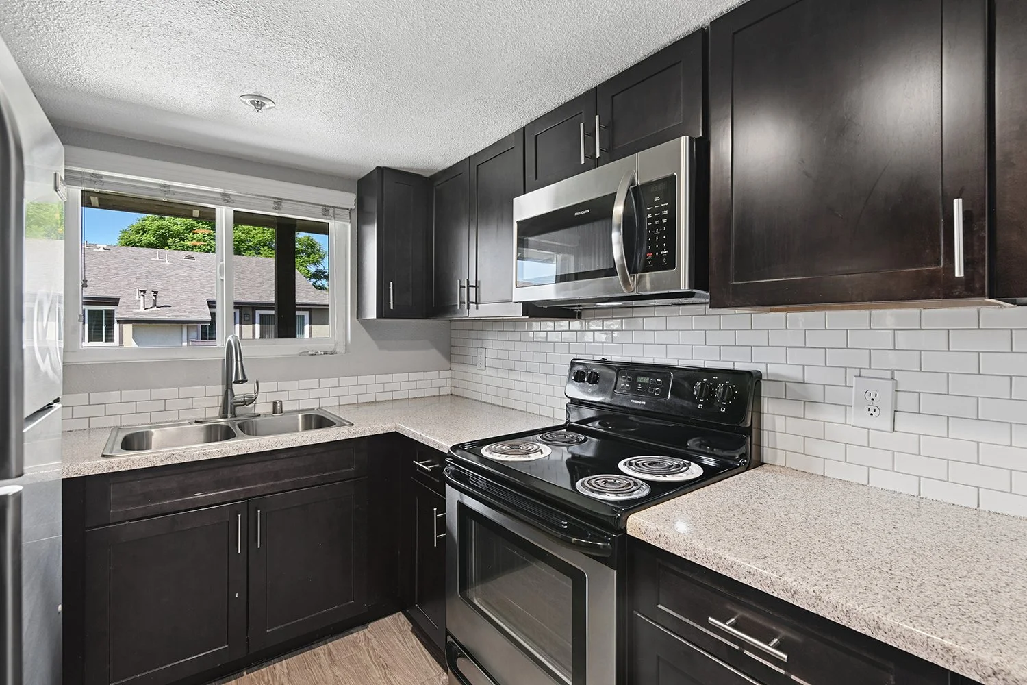 Kitchen in 1 Bedroom Citrus Heights Apartment homes with dark cabinetry, stainless appliances, and plank flooring for an elevated look. 
