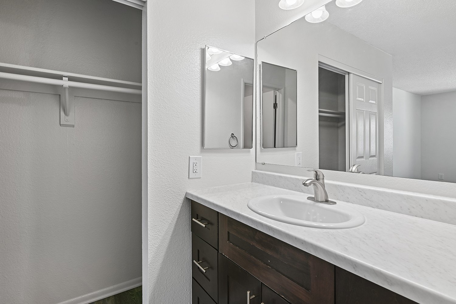 Private bathroom in Primary bedroom of Citrus Heights 3 Bedroom Apartment home with plank flooring, oversized vanity, quartz countertops and dark wood cabinetry.  
