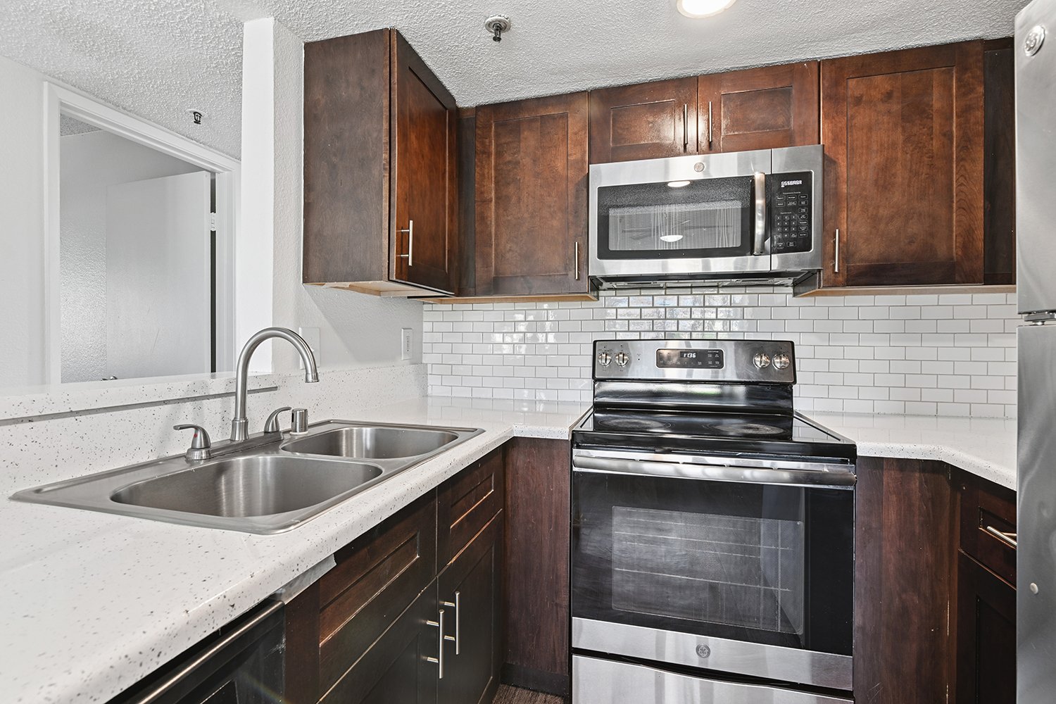 Gorgeous Kitchen in Citrus Heights Apartment Homes with plank flooring, quartz countertops, stainless appliances and dark wood cabinetry. 