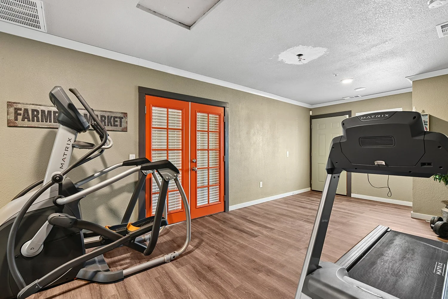 Fitness center at Citrus heights with plank flooring, wall mirror, treadmill and an elliptical. 