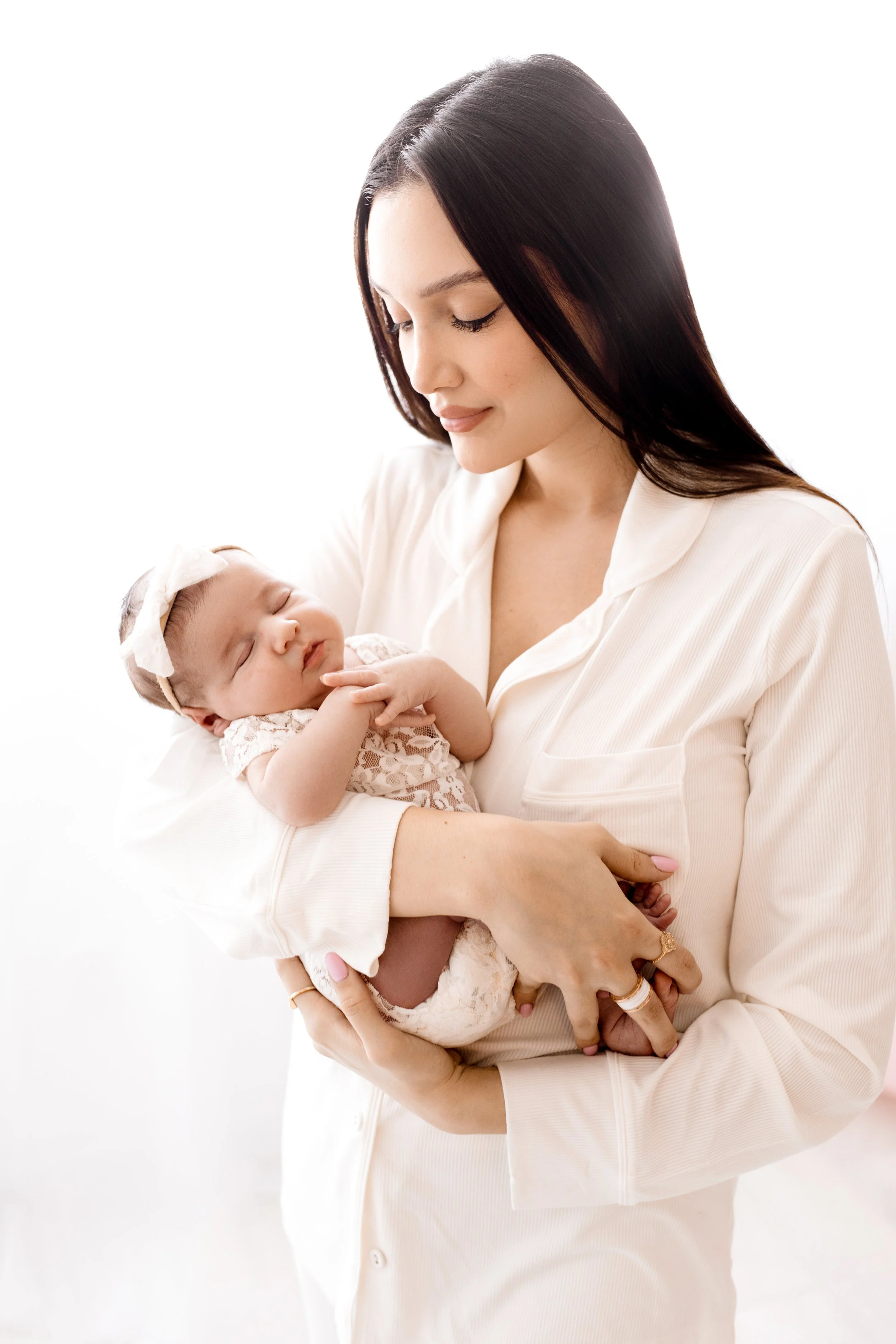 Mother holding her newborn baby in white outfit for a family portrait – professional maternity and newborn photography in Mississauga and the GTA.