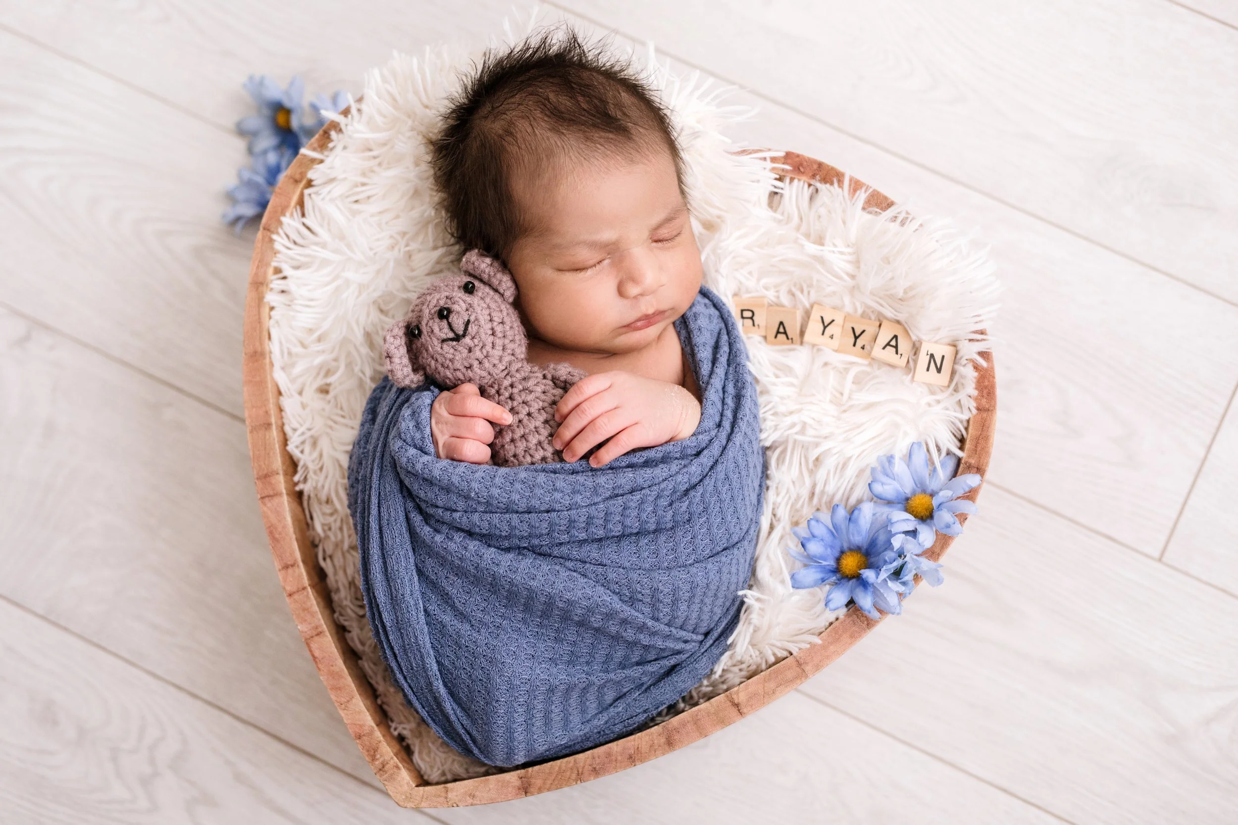 Black and white photo of a newborn baby cradled in multiple hands, with head and feet gently supported – professional newborn photography in Mississauga.
