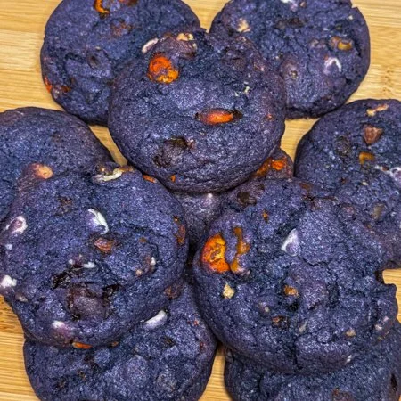 a pile of purple Halloween kitchen sink cookies on a wooden cutting board