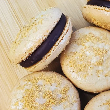 close up of s'mores macarons with one tipped on its side so you can see the ganache filling