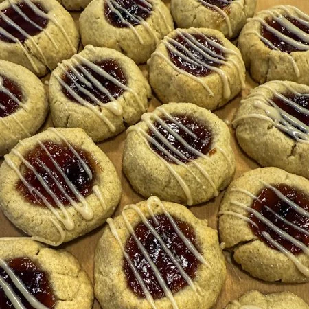 overhead shot of plum cardamom thumbprint cookies with an icing drizzle