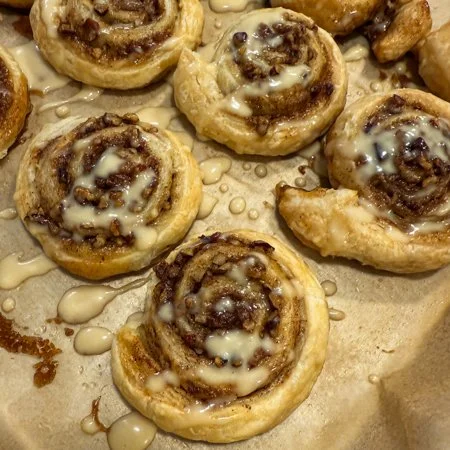 overhead shot of maple pecan puff pastry pinwheels with a cream cheese icing drizzle