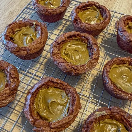 brownie cups filled with pistachio cream on a wire cooling rack