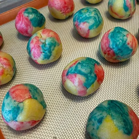tie dye cookie dough balls on a baking sheet