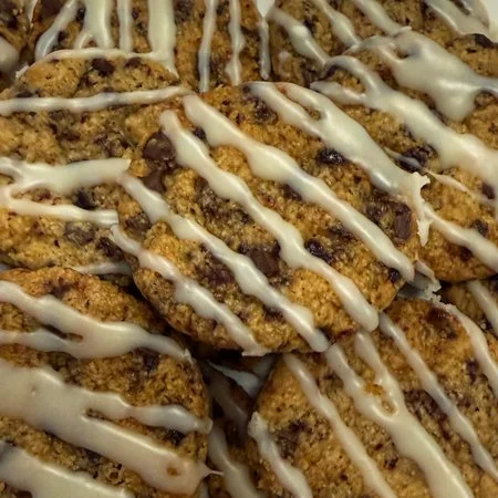 close up of a pile of cherry chocolate almond cookies with white chocolate icing drizzle
