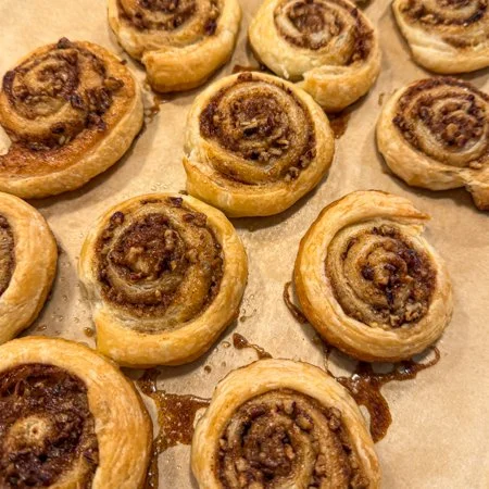 baked maple pecan puff pastry pinwheels on a parchment paper without icing