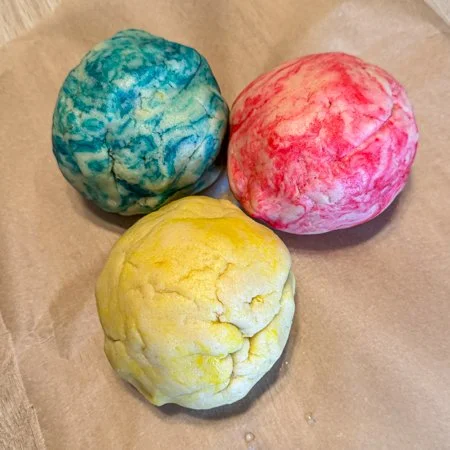blue, yellow, and pink dyed balls of cookie dough