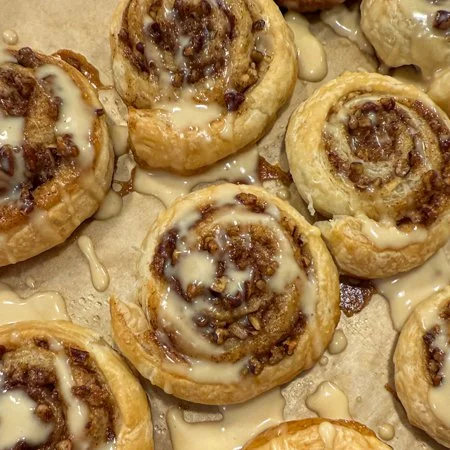 overhead shot of maple pecan puff pastry pinwheels with a cream cheese icing drizzle