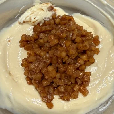 cooked apples in a bowl on top of cheesecake batter