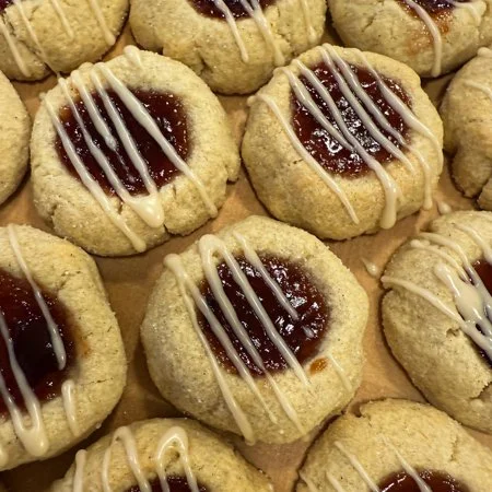 close up of plum cardamom thumbprint cookies with an icing drizzle