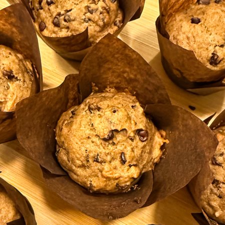 overhead shot of peanut butter, date, and banana muffins on a wooden cutting board