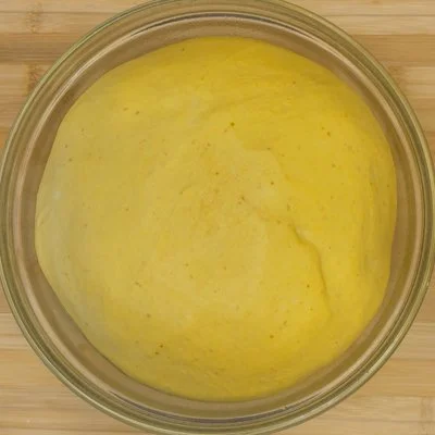 pumpkin bread dough in a clear bowl after it has proofed and doubled in size