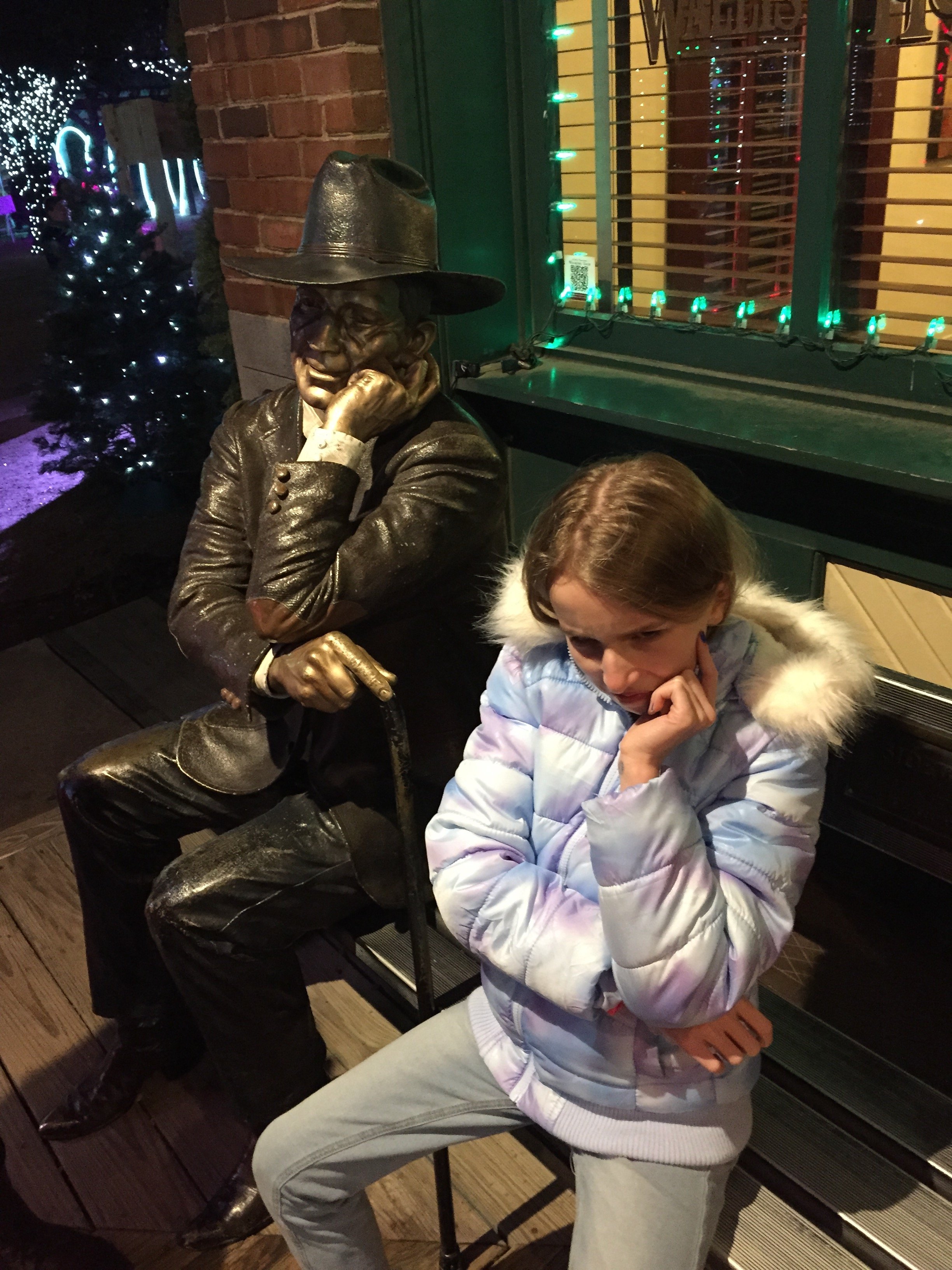 " Monkey See, Monkey Do " Young girl mirrors the thoughtful  pose of a bronze statue in a candid street scene.