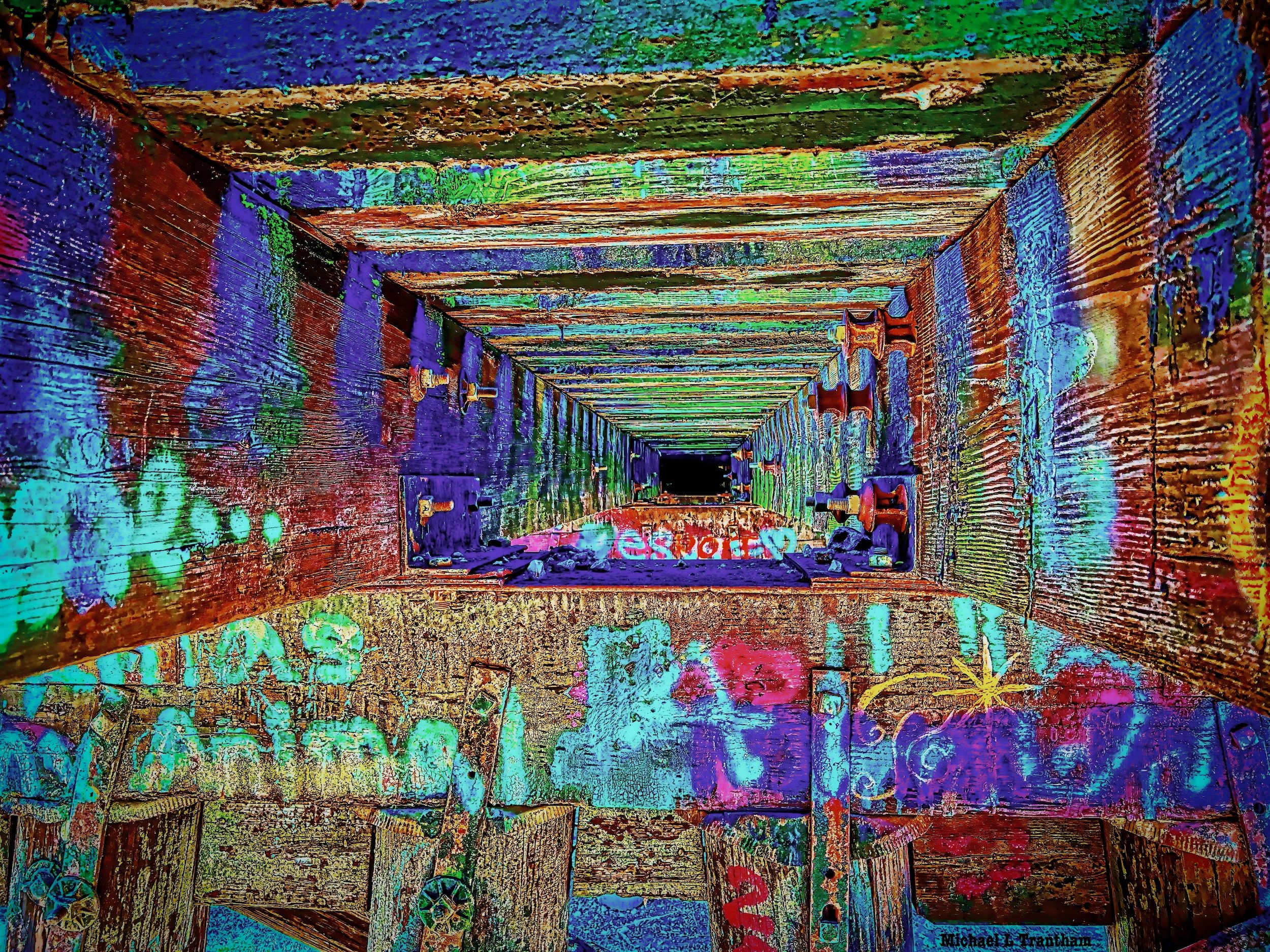 "Vanishing Point"  Vivid graffiti beneath a railroad trestle transforms weathered timbers into colorful mystery