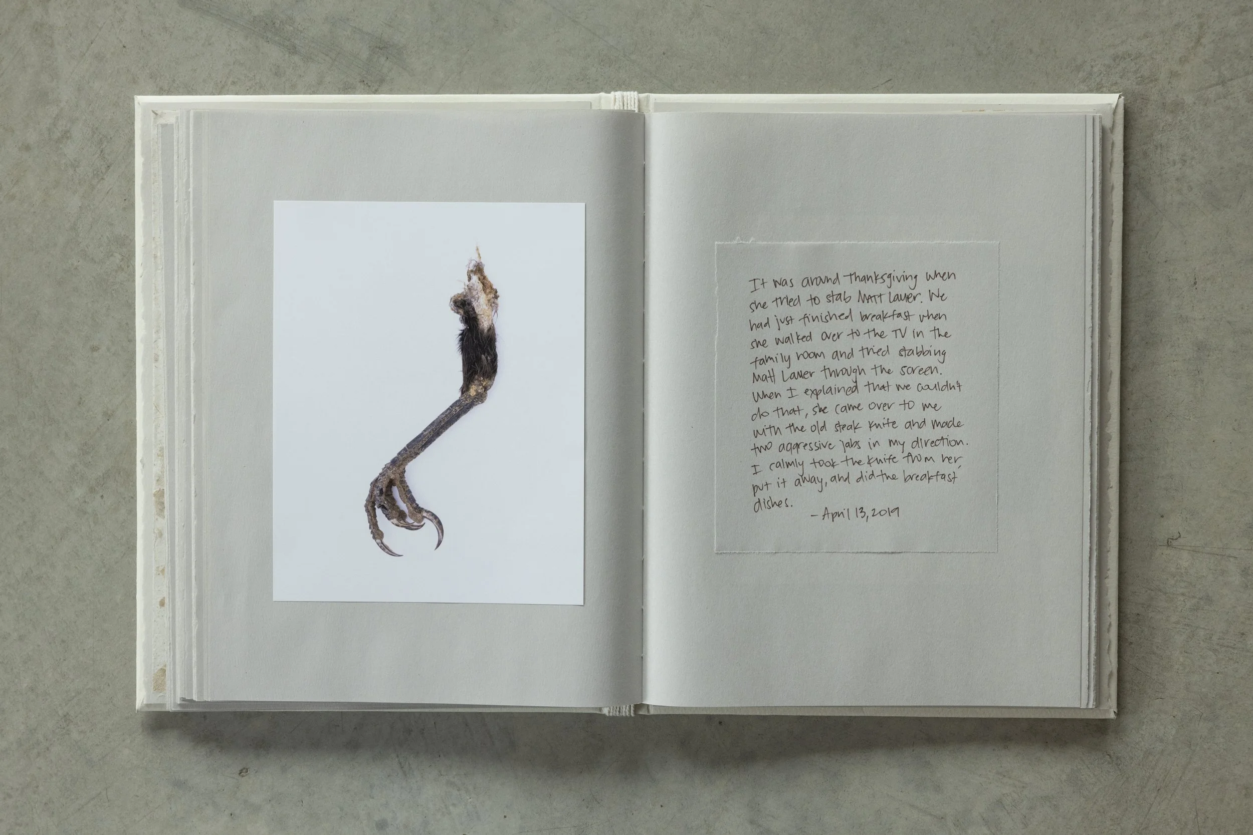 Open notebook with a photograph of a matchstick on the left page and handwritten story on the right page. The background is a gray surface.