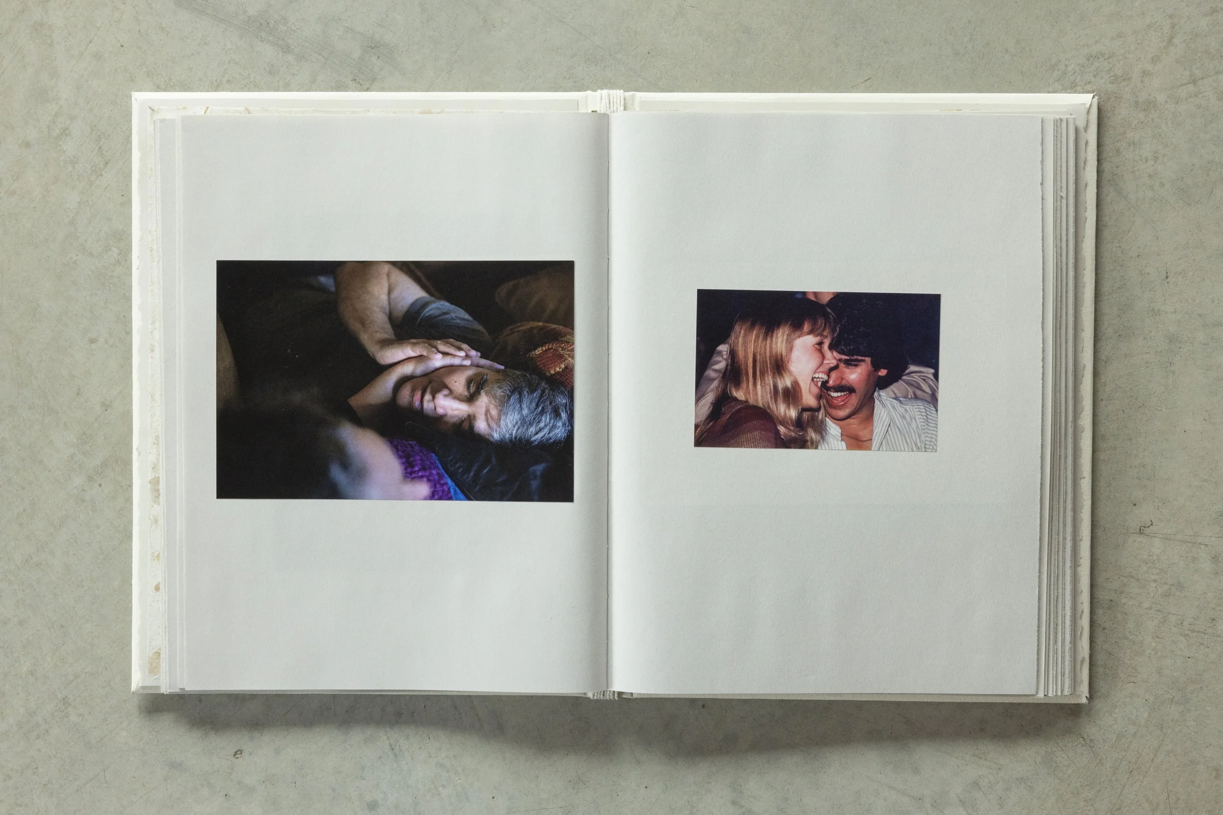 Open photo album showing two pictures: one of a person with gray hair lying down with their hand on their head, and another of a smiling woman with long blonde hair and a man with dark hair sharing a laugh.