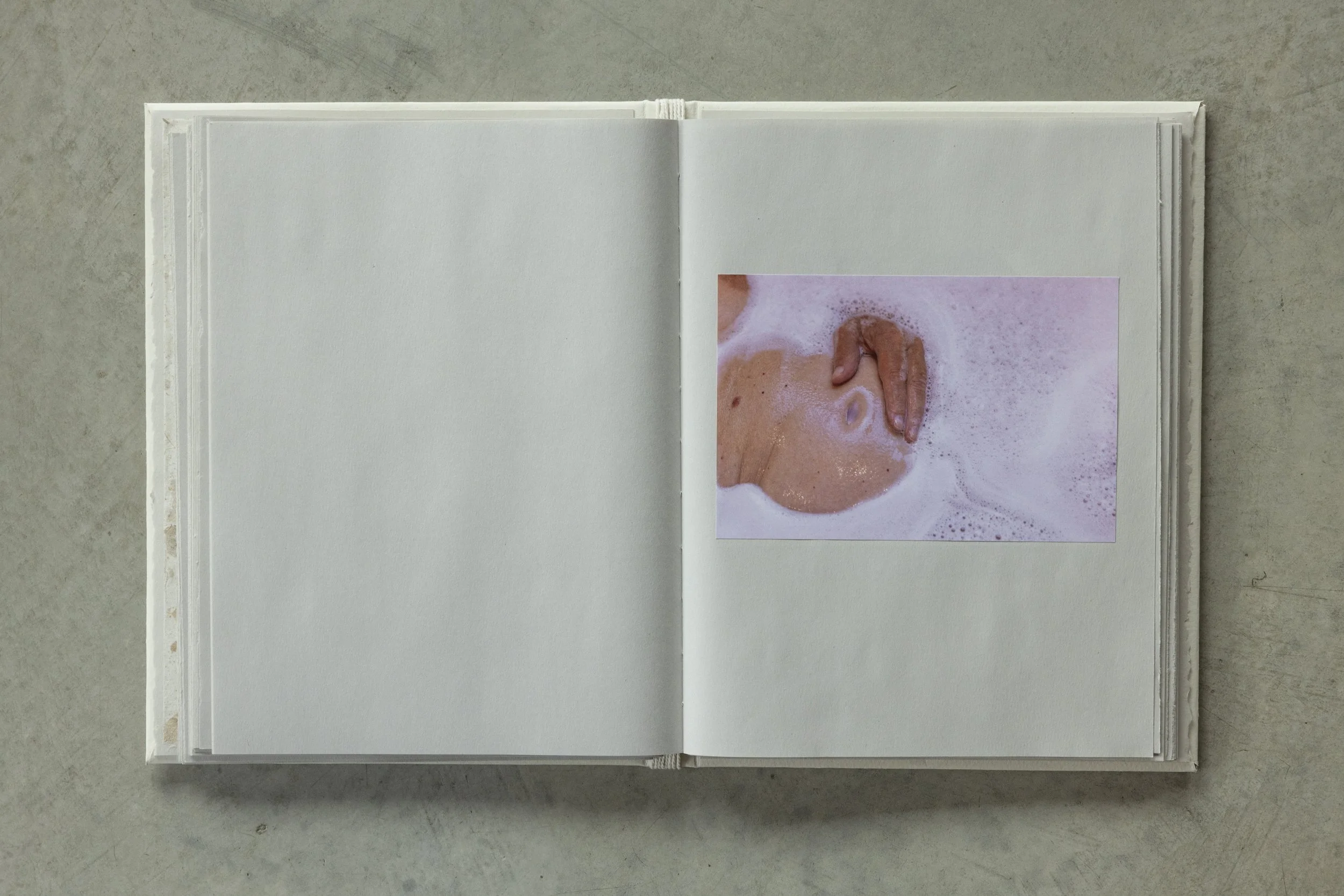 Open photo album with blank pages and a small picture of soap bubbles on human skin in the lower right corner.